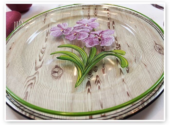 Platos de cristal francés pintados a mano con orquídeas, sobre unos de porcelana de falsa madera (diseño de Alberto Pinto)