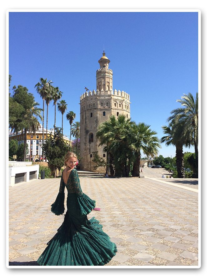 María León junto a la Torre del oro vestida de flamenca