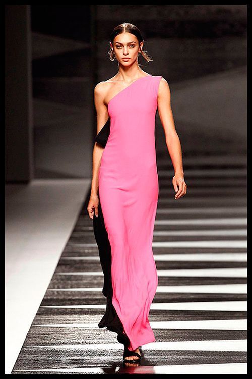 JUANJO OLIVA. Nos propone un look muy setentero con este espectacular vestido en fucsia y negro con hombro al aire. Yo me lo pondría para una súper fiesta.